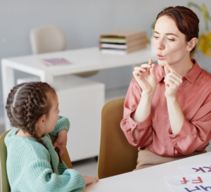 Woman teaching a word to a young girl using her hands to demonstrate